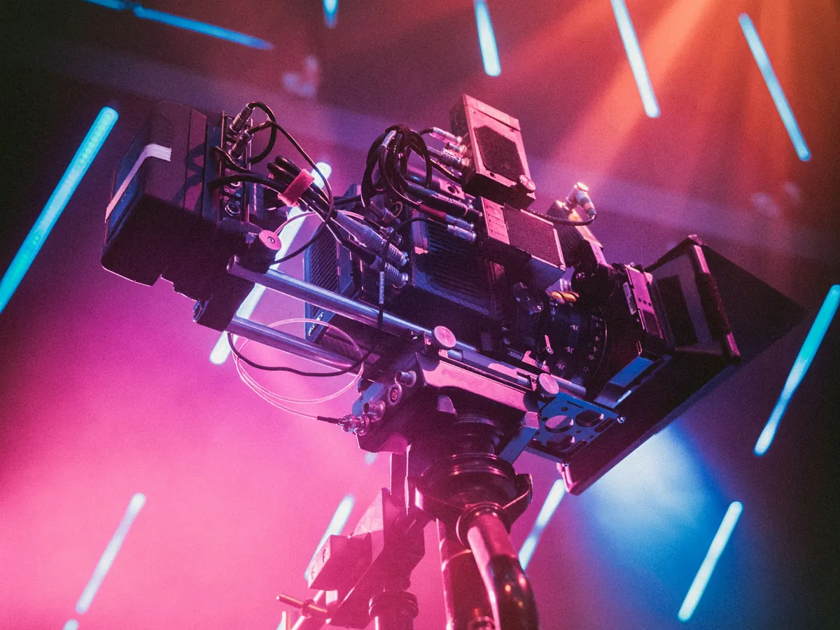 Kamera filmowa na statywie sfotografowana od dołu, w różowym i niebieskim świetle